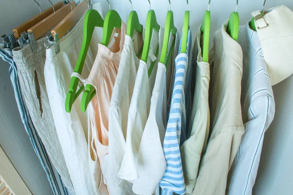 Summer wardrobe with linnen clothes on green hangers — Stock Photo, Image
