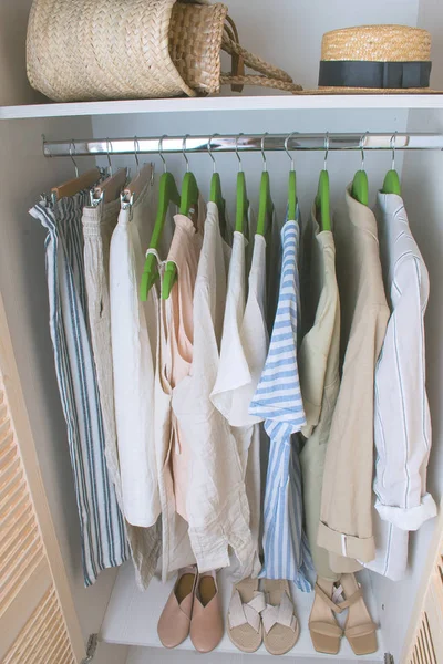 Zomergarderobe met linnen kleding op groene hangers — Stockfoto