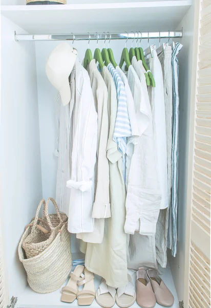 Summer wardrobe with linnen clothes on green hangers — Stock Photo, Image