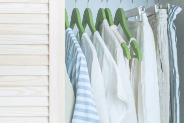 Yeşil askılarda keten giysiler olan bir gardırop.