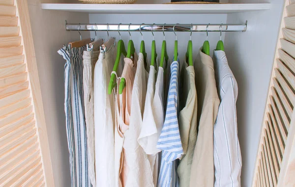 Guarda-roupa de verão com roupas de linho em cabides verdes — Fotografia de Stock