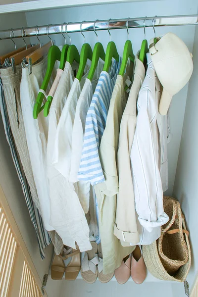 Zomergarderobe met linnen kleding op groene hangers — Stockfoto