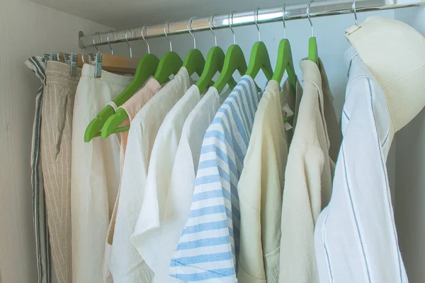 Zomergarderobe met linnen kleding op groene hangers — Stockfoto