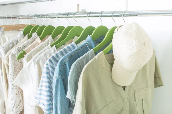 Summer wardrobe with linnen clothes on green hangers — Stock Photo, Image