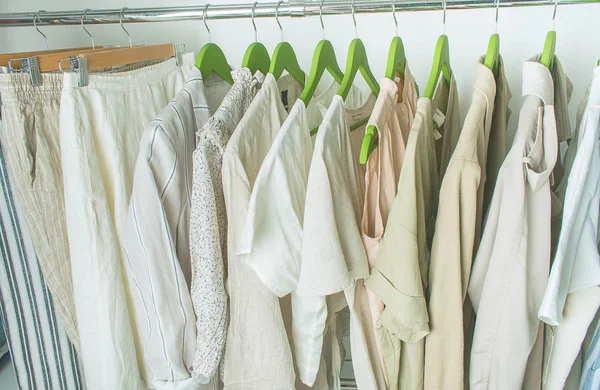 Guarda-roupa de verão com roupas de linho em cabides verdes — Fotografia de Stock