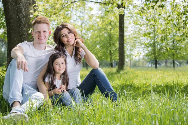 Portret Szczęśliwą Rodzinę Siedząc Trawie Pod Drzewem Parku Słoneczny Dzień — Zdjęcie stockowe
