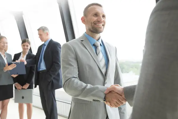商界人士握手和微笑 结束了在办公室的会议 — 图库照片