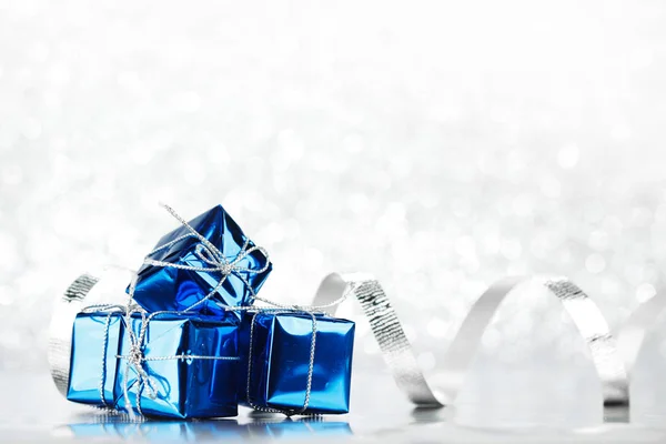 Kleine Schachteln Mit Dekorativen Weihnachtsgeschenken Auf Silbernem Bokeh Hintergrund — Stockfoto