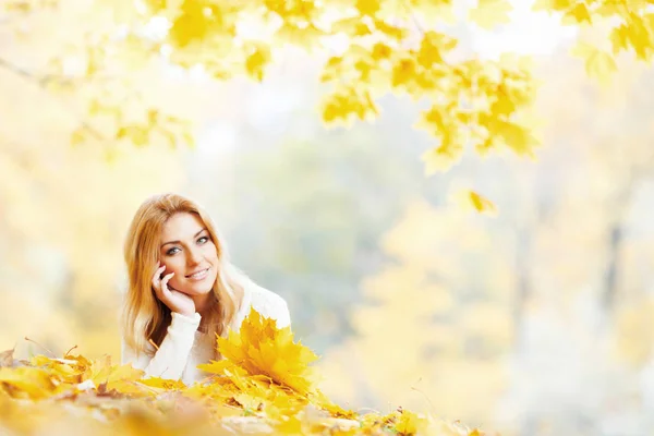 美丽的年轻女子躺在黄色的叶子在秋天的公园 — 图库照片