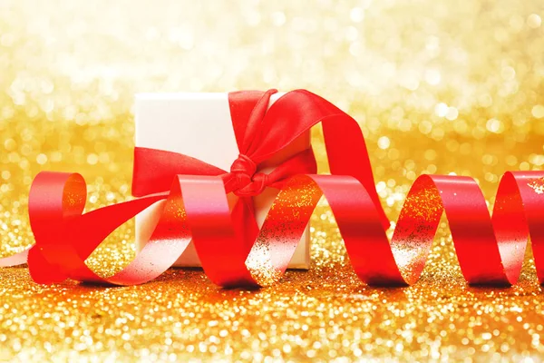 Weiße Geschenkbox Mit Roter Schleife Auf Goldenem Glitzerhintergrund — Stockfoto