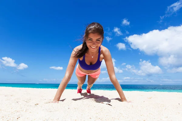 魅力的な若い女性がビーチで練習を押し上げ 晴れた日にフィットし続ける — ストック写真