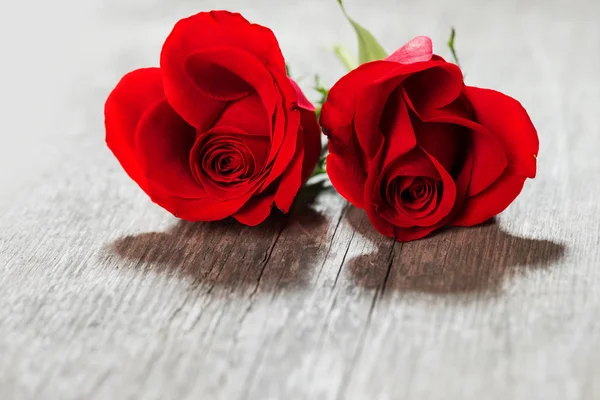 Duas Rosas Vermelhas Deitadas Uma Mesa Madeira Perto — Fotografia de Stock