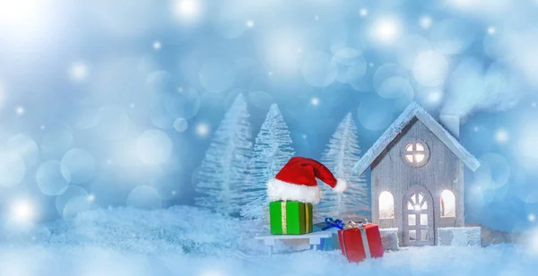 圣诞贺卡 上面装饰着舒适的小房子 礼物和圣诞老人的帽子 雪橇上覆盖着童话般的冬季冷杉森林背景和飘落的雪花 新年设计明信片 文本的复制空间 — 图库照片