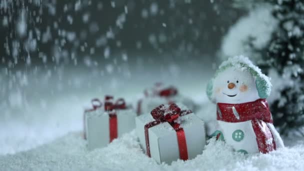 雪人冷杉树和圣诞节礼物在降雪的雪上漂泊 — 图库视频影像