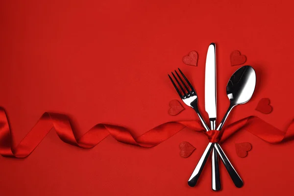 用丝带和红心系在红色背景下的餐具套装情人节晚餐的概念 — 图库照片