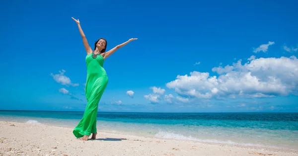 身穿绿色衣服的妇女举臂在热带海滩上摆姿势 — 图库照片