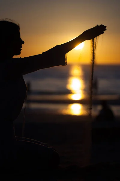 Girl pouring sand at sunset — Stock Photo, Image