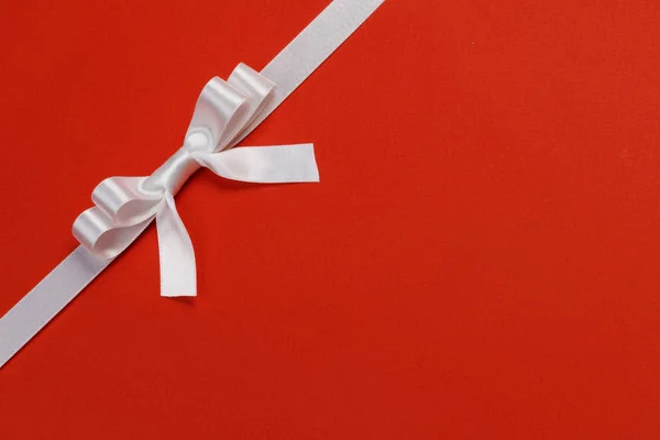 White gift bow on red