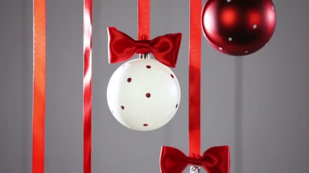 灰色の背景に弓のリボンでぶら下がるクリスマスボール — ストック動画