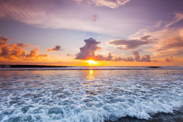 夕阳西下沙滩上的海浪 躲在云彩后面的太阳 — 图库照片