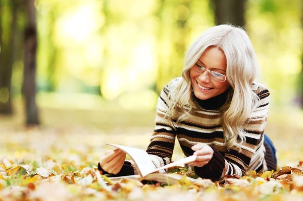 女人在秋天的公园里看书 — 图库照片