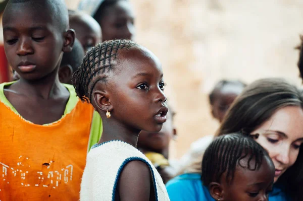 Bílé kavkazské mladá žena si hraje s afrických černochů v odlehlé vesnici — Stock fotografie