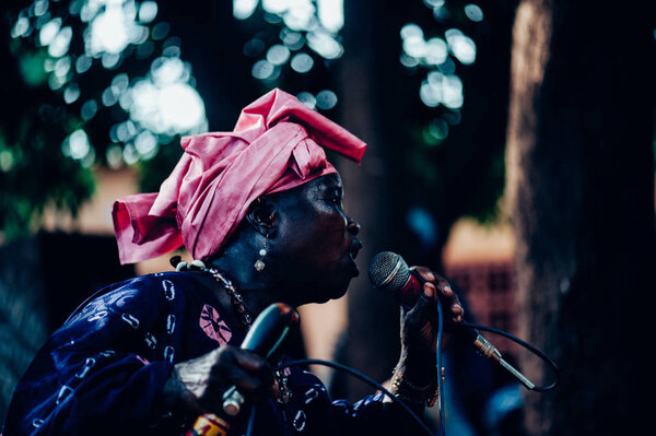Black woman singing and dancing with a mic. Multi Ethnic music party to celebrate western and developing countries cooperation. Bamako, Mali. Africa