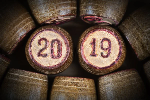 Vintage wooden lotto kegs with two numbers 20 and 19 as symbol of 2019 year. Close-up top view of 2019 New Year inscription in circle with pink trim. Vignette and trendy brown toning.
