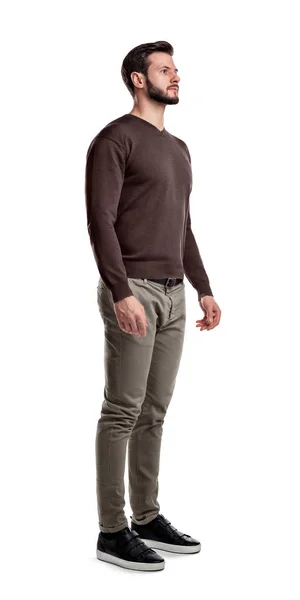 Un giovane uomo in maglione e pantaloni cargo sta guardando davanti in vista a metà girato su uno sfondo bianco . — Foto Stock