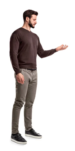 Un hombre joven en moda casual cierra se para en una vista lateral y mira una mano apareció como si estuviera sosteniendo algo . — Foto de Stock
