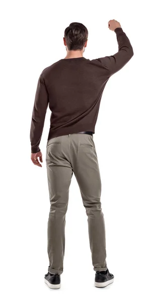 A fit man in casual sweater stands in a back view with one arm lifted up as if holding something in front of him. — Stock Photo, Image