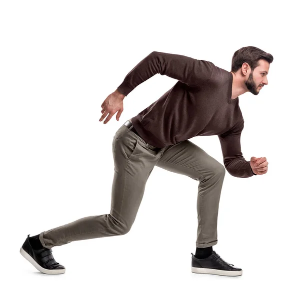 Um homem em forma de barba em roupas casuais está em uma posição baixa pronto para correr em um fundo branco . — Fotografia de Stock