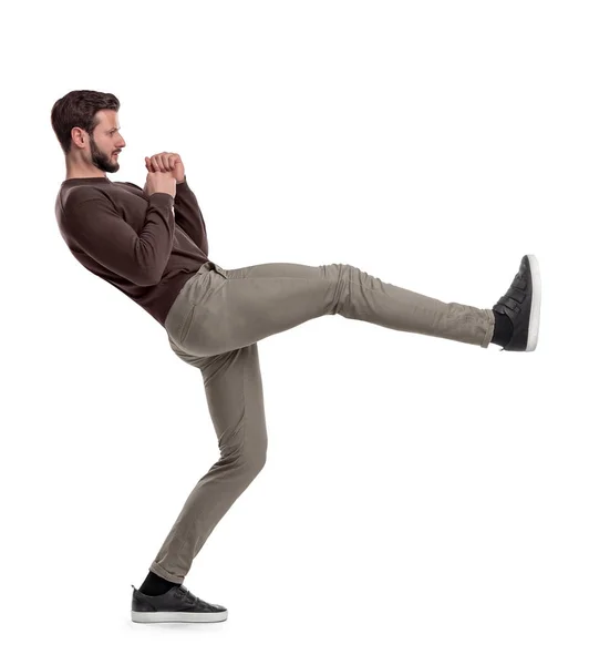 Un hombre barbudo aislado con ropa casual está parado sobre un fondo blanco en medio de la patada en la pierna . —  Fotos de Stock