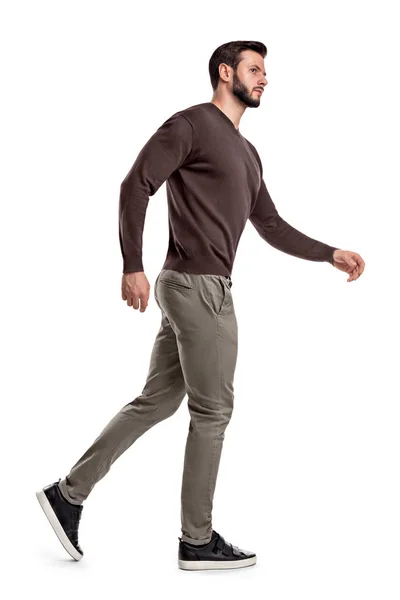 Un hombre barbudo con atuendo casual camina con una vista lateral y mira sospechosamente hacia los lados . —  Fotos de Stock