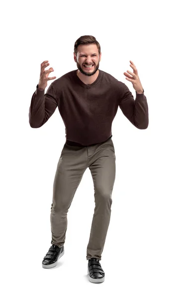 An aggressive bearded man in casual clothes shouts at camera, shows his teeth holds his hands near his head. — Stock Photo, Image