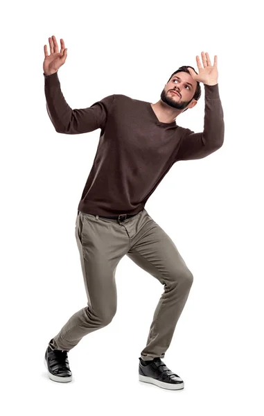 A bearded man in casual garb stands cowering under something dangerous above him. — Stock Photo, Image