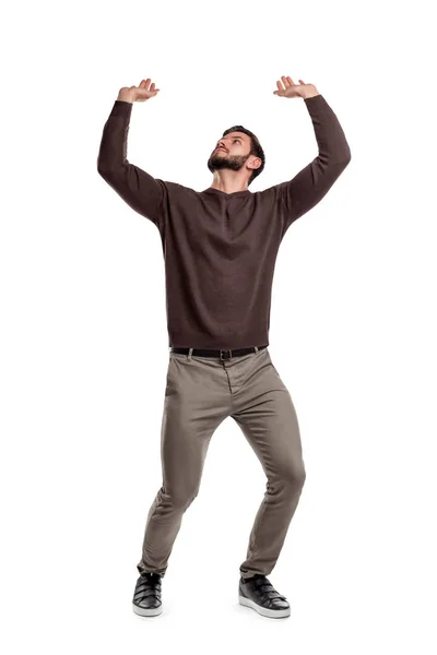 Um homem barbudo em roupas casuais tenta segurar algo pesado de cima em um fundo branco . — Fotografia de Stock