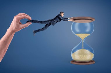 Bir işadamı dev bir el onu uzaklara sürükler çünkü büyük kum tutmak başarısız.