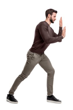 Sakallı bir adam rahat pantolon presler ellerini görünmez bir nesnenin üzerine taşımak için uygun.