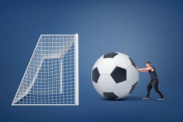 Un pequeño hombre en forma empuja una pelota de fútbol gigante hacia una gran puerta vacía . — Foto de Stock