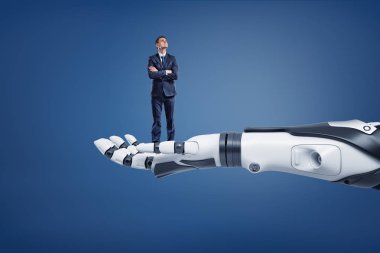 Büyük bir robot kol üzerinde dururken küçük düşünme işadamı bakar.