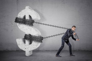 Onun yerden büyük bir beton dolar işareti taşımaya çalışıyor bir zinciri bir işadamı tugs.