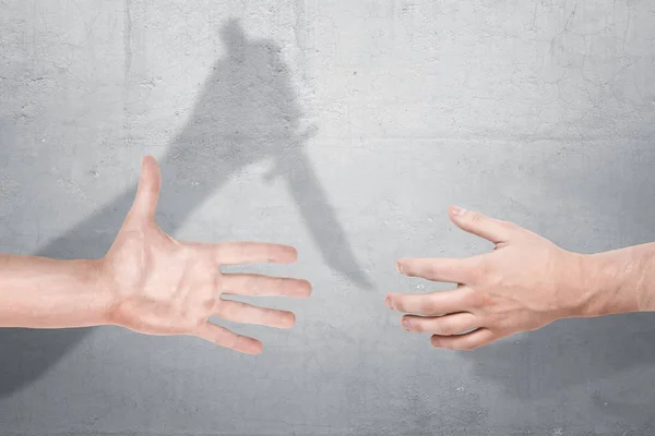 İki erkek ellerini almak için bir el sıkışma bir elin elinde bir bıçakla bir beton zemin üzerine bir gölge ile yakın.