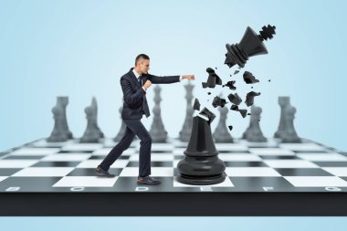 Küçük bir işadamı bir satranç tahtası üzerinde duruyor ve küçük parçalar halinde yok eder ve büyük bir siyah Kral vurur.