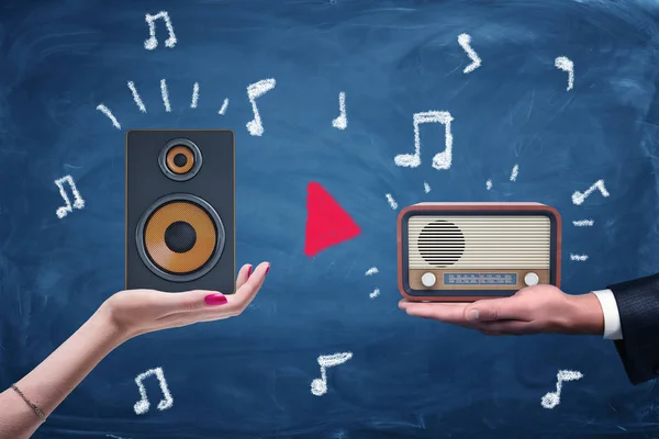 Una mano femenina y una mano masculina sosteniendo un altavoz de audio moderno y un set de radio retro . — Foto de Stock