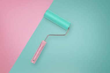 Nane renkli boya silindiri pembe kulplu pembe bir bölümle bir nane arka plan üzerinde yatıyor.