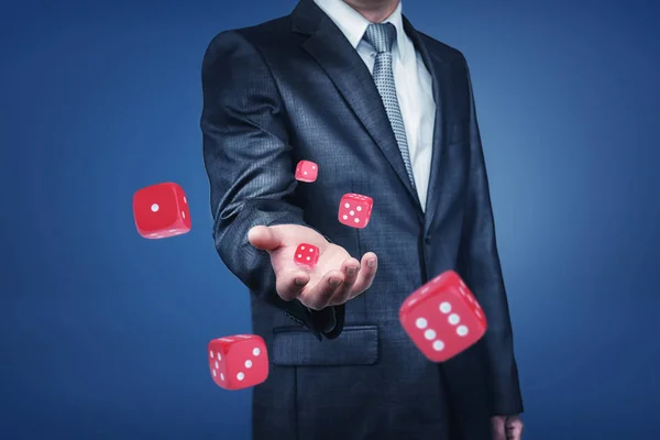 Un brazo de hombre de negocios lanzando muchos dados rojos de casino al frente en una vista cercana . — Foto de Stock