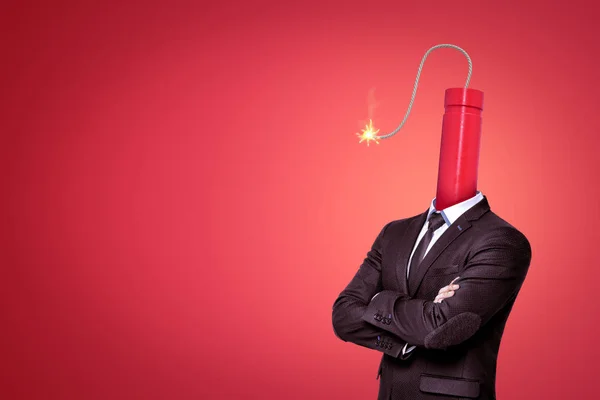 A waste-deep image of a businessman with a big dynamite stick with its wick burning instead of head on red background with a lot of copy space.