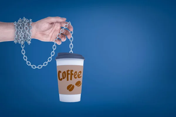 Close-up de mão segurando xícara de papel de café na cadeia de metal que também é enrolado em torno do pulso . — Fotografia de Stock