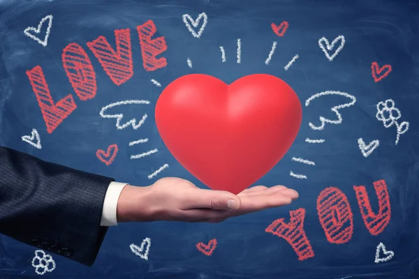 Erkek el Love You tebeşir ile kırmızı kalp işareti ve kalp çizimleri mavi arka plan üzerinde tutarak. — Stok fotoğraf